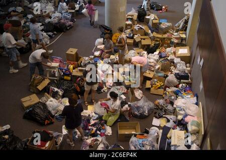 Austin, Texas USA, 3 settembre 2005: I rifugiati dell'uragano Katrina continuano a riversarsi nei rifugi texani, tra cui l'Austin Convention Center, che aspetta più di 5.000 persone nei prossimi tre giorni. Le forniture di soccorso donate dagli Austinites spazzano via il pavimento del Centro Congressi di Austin mentre i volontari cercano di ordinare e organizzare il contenuto delle scatole. ©Bob Daemmrich Foto Stock