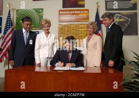 Austin, Texas USA, 13 giugno 2005: Il governatore del Texas Rick Perry (al centro, seduto) firma un disegno di legge che stimola gli investimenti nell'industria high-tech del Texas. La firma del disegno di legge avviene presso l'impianto di produzione di semiconduttori Samsung da 1,3 miliardi di dollari nella periferia nord di Austin. Da sinistra a destra ci sono il direttore dello stabilimento H.K. Park, la Rep. Di Stato Jeanne Morrison, il Governatore Perry, il Senatore di Stato Florence Shapiro e il Rep. Michael McCaul. ©Bob Daemmrich Foto Stock