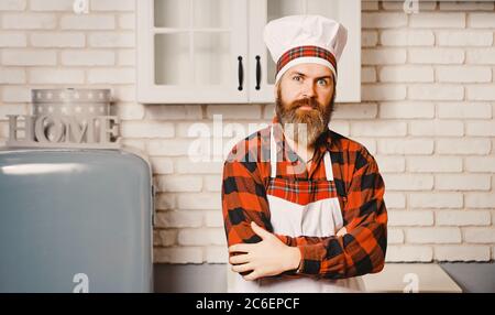 Un giovane uomo con il bearded, vestito con una camicia rossa e un grembiule bianco. Foto Stock