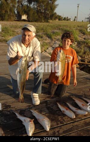 Port Mansfield, Texas USA, 12 luglio 2005: Nonno e nipote che tengono trote maculate alla fine di una lunga giornata di pesca sulla costa texana a Port Mansfield, Willacy County, Texas. ©Bob Daemmrich Foto Stock