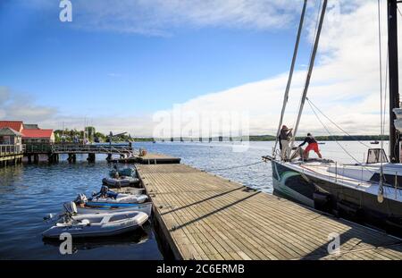 Gli uomini che navigano nel porto con barche e attracco in estate, Castine, Maine, New England, USA Foto Stock