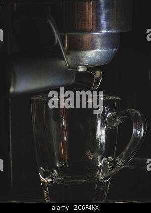 Svuotare la tazza di vetro dell'espresso nella macchina, preparare caffè caldo Foto Stock