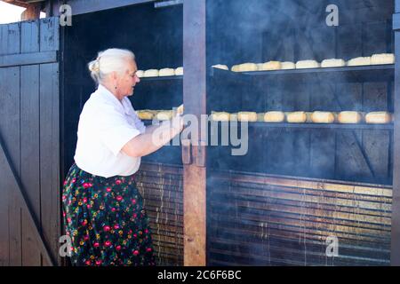 Monti Tatra, Polonia: 30 2018 luglio - UN contadino polacco sta facendo il famoso formaggio oscipek all'aperto nelle regioni di Zakopane. Oscypek è fatto usando sal Foto Stock