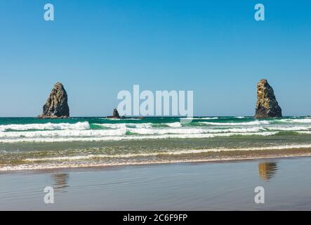 Le rocce di Sea Stack si ergono alte mentre le onde si tuffano su Cannon Beach in Oregon Foto Stock