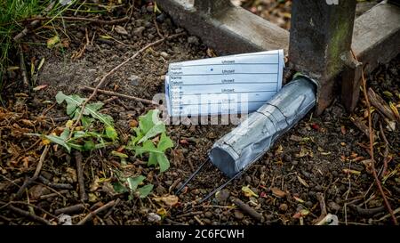 contenitore di geocache racchiuso con nastro per condotti e logbook nascosti all'interno di una recinzione Foto Stock