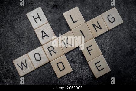 piastrelle di legno per lettere che formano parole su una superficie di ghisa grigia sullo sfondo, lavorando a lungo Foto Stock