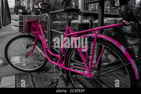 fotografia in bianco e nero di una bicicletta rosa in stile olandese bloccata a una ringhiera a busanbrücke, nell'hafencity di amburgo, in una giornata piovosa Foto Stock