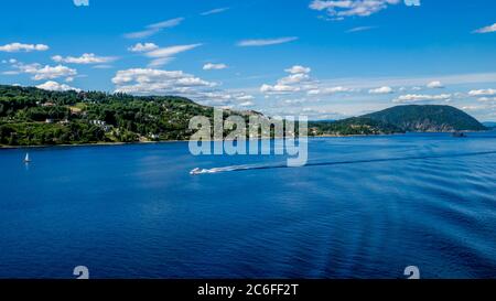 panorama del oslofjord con due barche bianche di fronte a verdi colline con case vicino a saetre, norvegia Foto Stock