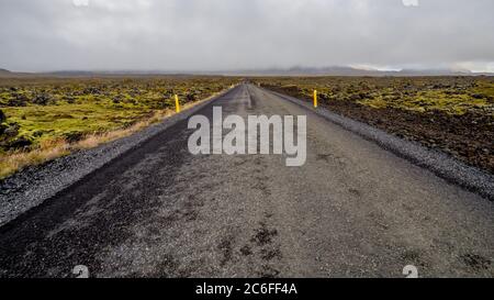 Una strada asfaltata vuota e diritta conduce attraverso campi di lava infiniti, adsorti di muschio verde nella penisola di snaefellsnes in islanda Foto Stock