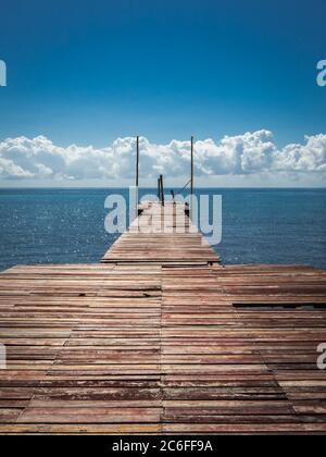 il palco di atterraggio perso con tavole stagne raggiunge direttamente il mare blu marino dei caraibi Foto Stock