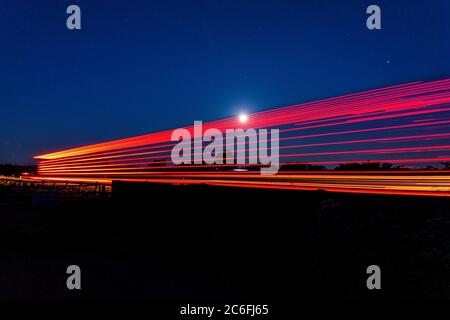 Luna che brilla attraverso i sentieri di luce da un carro sulla a66 Foto Stock