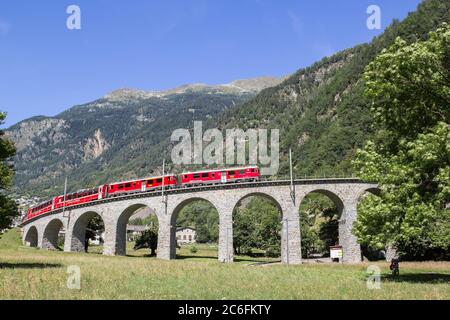 Brusio, Svizzera: 26 agosto 2018 - il treno Bernina Express attraversa il famoso viadotto circolare delle Alpi svizzere, Brusio, Canton Grison Foto Stock