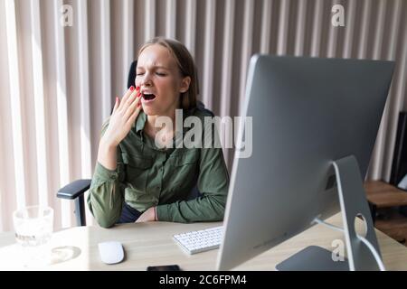 Giovane donna che brama lavorare il suo pc in ufficio Foto Stock