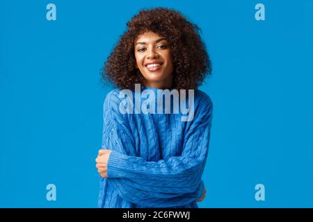 Romantica e carina, splendida donna afroamericana con acconciature in inverno maglione bello, abbracciando il proprio corpo e sorridendo, sempre caldo Foto Stock