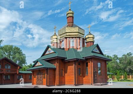 Piccola chiesa di tronchi con tre cupole dorate in giornata di sole Foto Stock