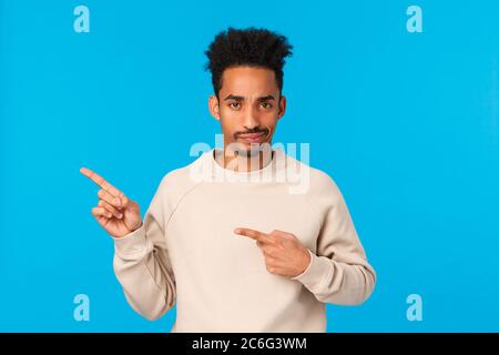 Scettici, gravi-cercando e deluso afro-americano moderno hipster ragazzo con taglio di capelli afro, smirk e accigliata insoddisfatto, di puntamento a sinistra Foto Stock