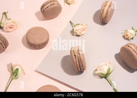 Macaron da dessert francese con fiori di rosa. Biscotti di mandorle al cioccolato. Disposizione piatta Foto Stock