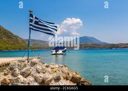 Lago Vouliagmeni e bandiera greca vicino Loutraki in una giornata estiva, Grecia Foto Stock