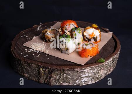 I panini giapponesi edp si trovano su un vassoio di legno, un rotolo di sushi con tonno, verdure e un guardaroba di salsa unagi cosparso di semi di sesamo Foto Stock