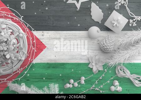 Bandiera palestinese su tavola di legno con oggetti neve. Natale e Capodanno, celebrazione nazionale concetto con decorazioni bianche. Foto Stock