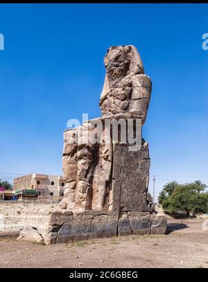 Il Colosso di Memnon, una delle due statue di pietra massiccia del faraone Amenhotep III situato nel tempio mortuario di Amenhotep III vicino Luxor Foto Stock