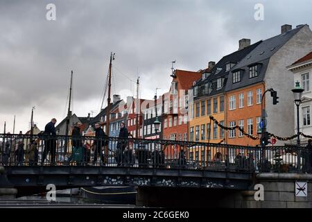 Le colorate case cittadine sul lato nord del canale di Nyhavn dietro il ponte. I montanti delle barche a vela possono essere visti anche contro i cieli grigi. Foto Stock