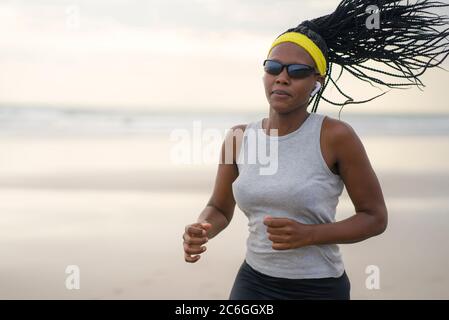 donna afroamericana che corre sulla spiaggia - giovane attraente e atletica ragazza nera che si allenano all'aperto facendo jogging allenamento in mare in fitness A.