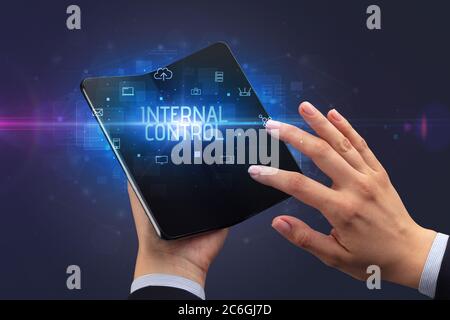 Imprenditore tenendo un pieghevole con smartphone il controllo interno iscrizione, cyber security concept Foto Stock