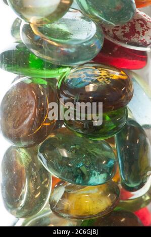 Le sfere di vetro multicolore sono viste da vicino e raggruppate insieme in un vaso di vetro contro uno sfondo bianco. Foto Stock