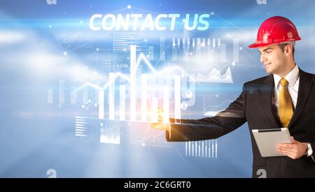 Bel uomo d'affari con casco disegno CONTATTACI iscrizione, architettura business plan concept Foto Stock