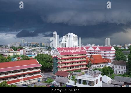 Nuvole monsoniche scure sono viste sopra (tempio) Wat Sam Phraya così come gli edifici residenziali vecchi e moderni nel distretto di Phra Nakhon, Bangkok, Thailandia Foto Stock