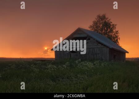 Il sole di mezzanotte si tramonta appena per risorgere la notte di metà estate nella Finlandia settentrionale. Foto Stock