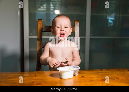 Adorabile bambino ragazzo mangiare formaggio cottage dal cucchiaio, sano snack latte. Foto Stock