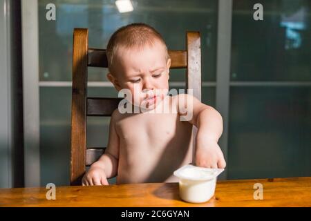 Adorabile bambino ragazzo mangiare formaggio cottage dal cucchiaio, sano snack latte. Foto Stock