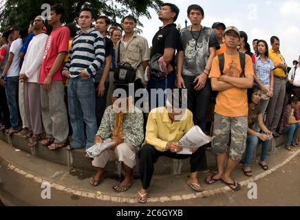 Vecchi uomini che leggono il giornale sul lato della strada dalla folla, 17 agosto 2009 giorno Nazionale Hari Kemerdekaan cerimonia, vicino al Palazzo Presidenziale, Jakarta Foto Stock