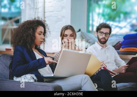 Tre giovani amici studenti amici seduti sul divano in camera Foto Stock