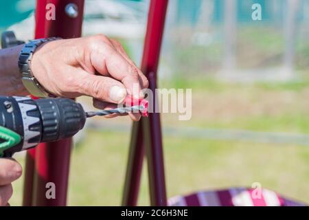 lavoratore fa un buco nel metallo con un trapano Foto Stock