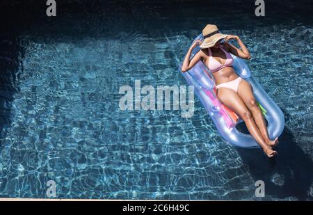Donna che galleggia su un anello gonfiabile in piscina Foto Stock