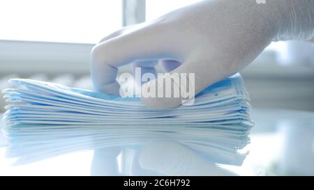 Il medico verifica un pacchetto di maschere chirurgiche controllandole una alla volta Foto Stock