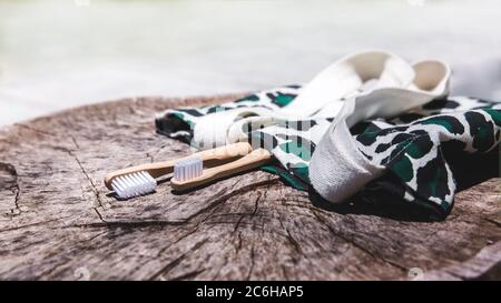 Due spazzolini da denti in legno di bambù ecologici, bianchi e gialli, su sfondo in eco-bag. Simbolo di stile di vita sostenibile senza plastica Foto Stock