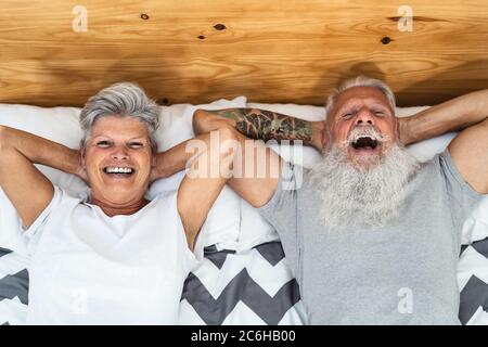 Felice coppia anziana a letto - Hipster persone mature che hanno divertente tempo a letto insieme - stile di vita anziano e concetto di relazione d'amore Foto Stock