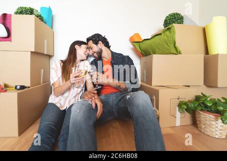 Felice giovane coppia che si muove in nuova casa per la prima volta - uomo e donna che festeggia con champagne in nuova casa di proprietà Foto Stock