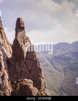 L'immagine mostra gli scalatori in azione scalando la formazione rocciosa di Napes Needle sul lato della montagna di Great Gable alla testa della valle di Wasdale nel Distretto Inglese del Lago essendo un obiettivo popolare come diritto di passaggio con gli scalatori di roccia di ogni generazione Foto Stock