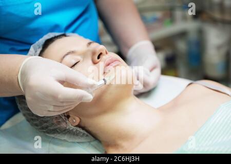 Estetista esegue un trattamento di mesoterapia con ago sul viso di una donna Foto Stock