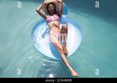 Donna che galleggia su un anello gonfiabile in piscina Foto Stock