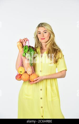 Negozio di alimentari. Borsa con generi alimentari. Borsa ecologica riutilizzabile. Consumo consapevole. Tendenza ecologica. Concetto di zero sprechi. Donna che tiene borsa della spesa con la stringa di frutta. Ragazza in abito borsa shopper. Sacchetto riutilizzabile. Foto Stock