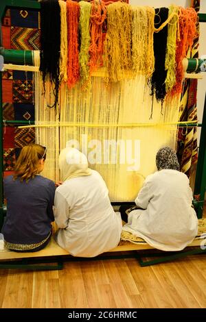 Marocco, donna sul telaio di tessitura in fabbrica di tappeti Foto Stock