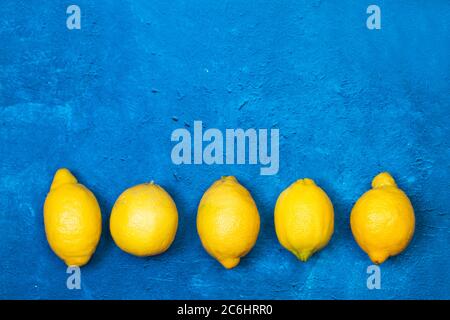 Cinque limoni su un classico sfondo blu testurizzato in una vista dall'alto Foto Stock