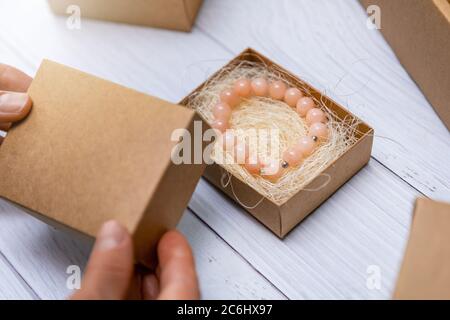 gioielli fatti a mano business - donna imballaggio bracciale perla in scatola di cartone per la spedizione Foto Stock