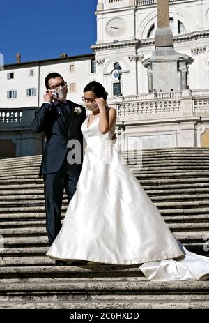Coppia sposata di recente con maschera medica Coronavirus, che posa per scattare foto sulla scalinata di Spagna. Matrimonio al tempo di Covid 19 Roma Italia Europa Foto Stock